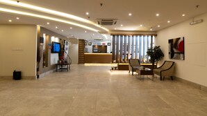 Un vestíbulo amplio con una recepción, zona de estar y una planta grande.
