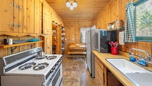 Eine kleine Küche mit Holzschränken, einem Herd, einem Kühlschrank und einer Spüle.