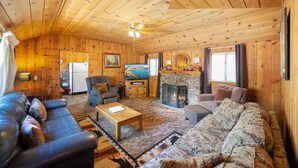Ein gemütliches Blockhaus-Interieur mit Kamin, Fernseher und einer komfortablen Sitzecke.