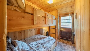 Ein Zimmer in einer Holzhütte mit einem Etagenbett, einem Schminktisch und einem Fenster.