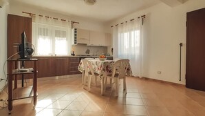 Een keuken met een eettafel, stoelen en een televisie op een standaard.