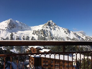 A mountain with snow-covered peaks and a wooden building with balconies in the foreground.