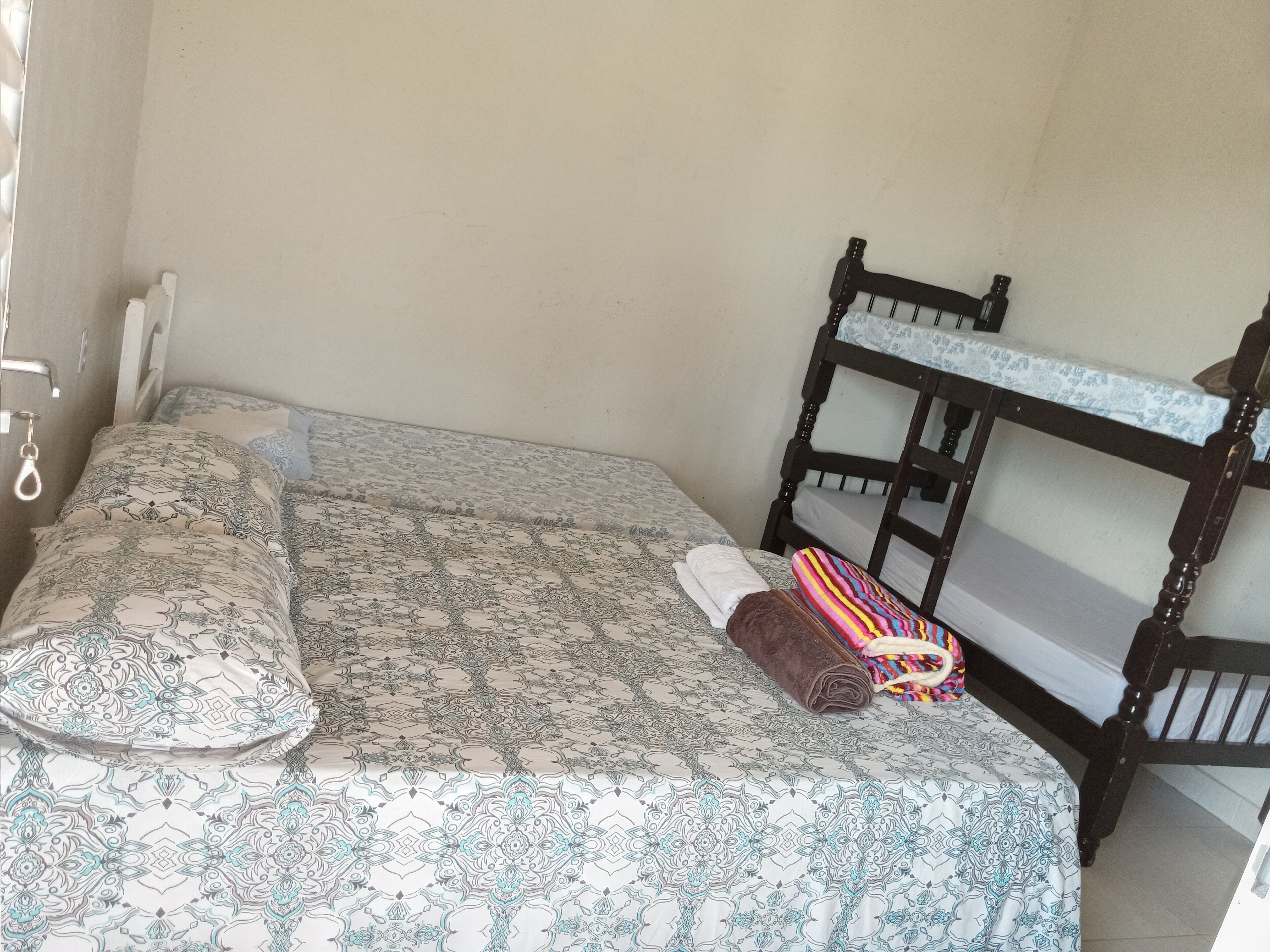 Una cama individual con ropa de cama estampada, un cabecero de madera y una toalla.