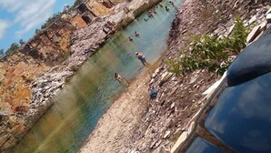 Paisaje rocoso con cielo azul despejado y una masa de agua.