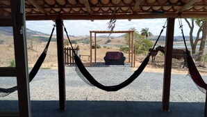 Una hamaca bajo una pérgola de madera con vistas a un paisaje rural, un área de estar cubierta y un suelo de grava.