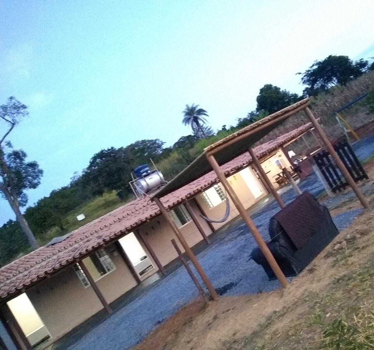A building with a tiled roof, a water tank on the roof, and a covered outdoor area with a bench.