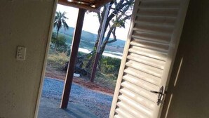Una habitación con cama, puerta que da al exterior y vista a palmeras y una playa.