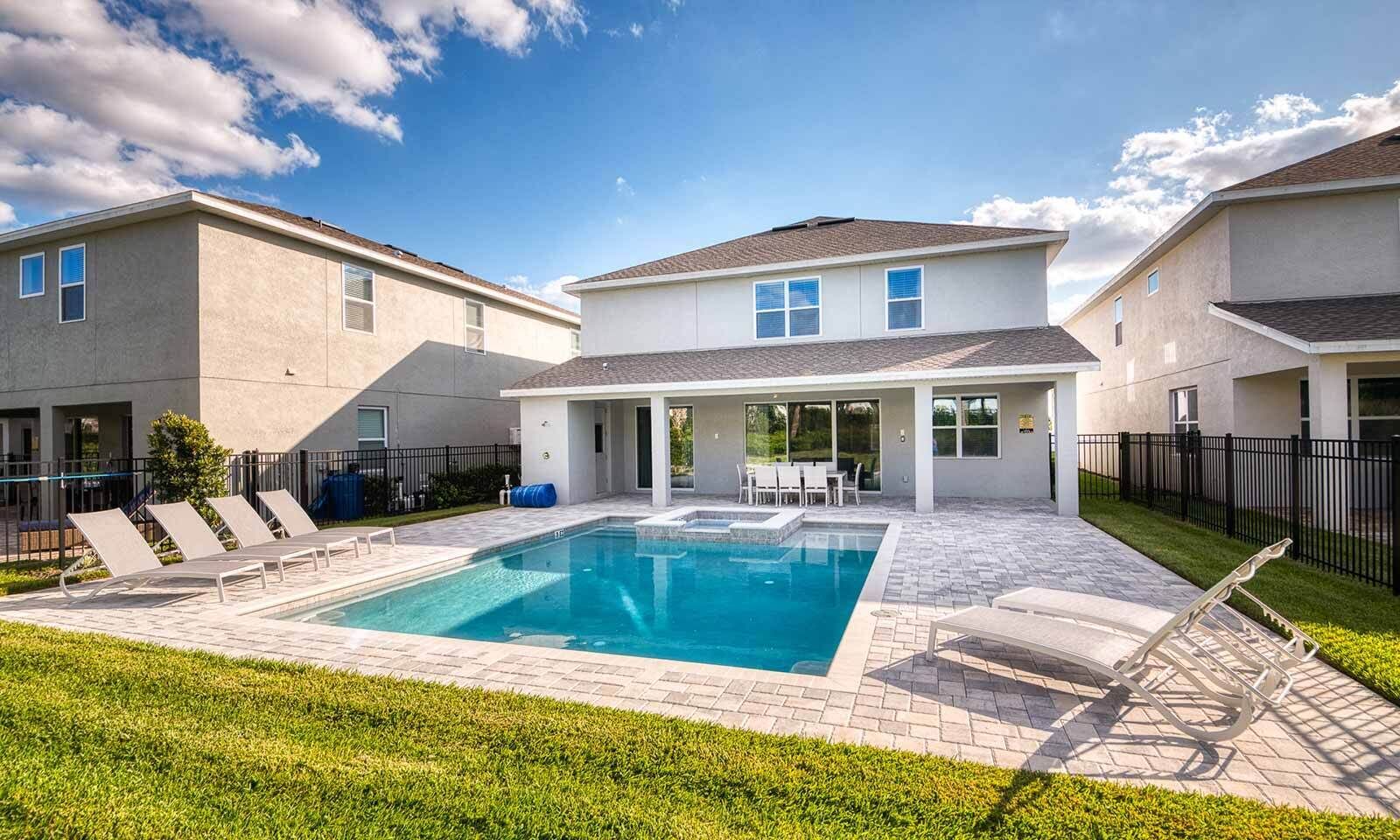 Edificio residencial con piscina, mobiliario de exterior y patio amurallado.