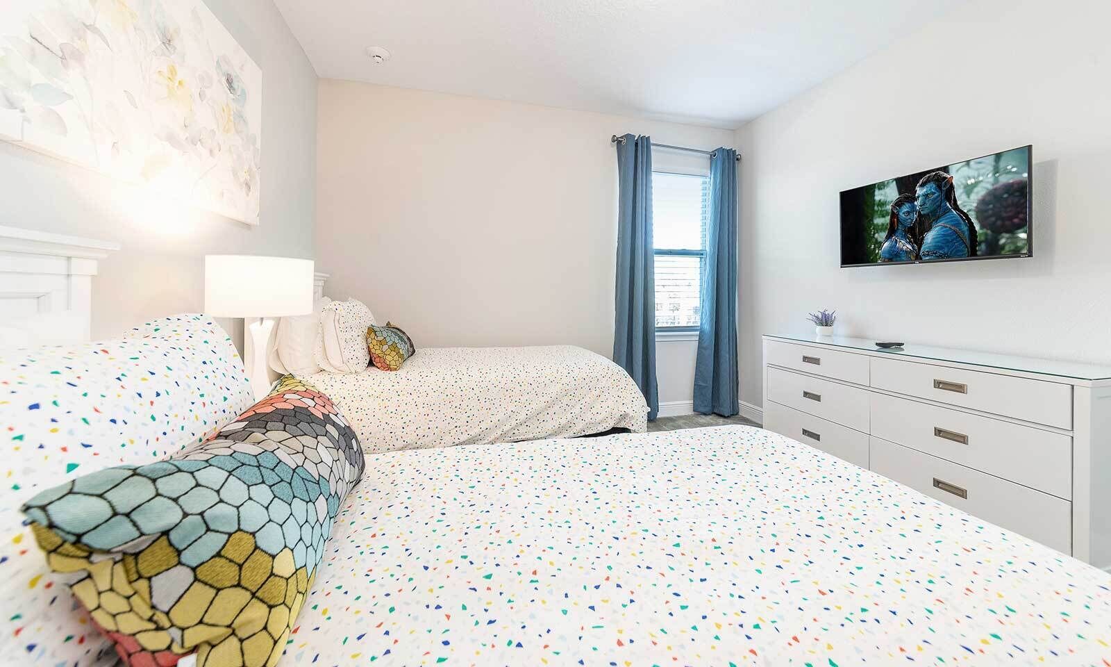 Een slaapkamer met een bed, een dressoir, een televisie en een raam met gordijnen.