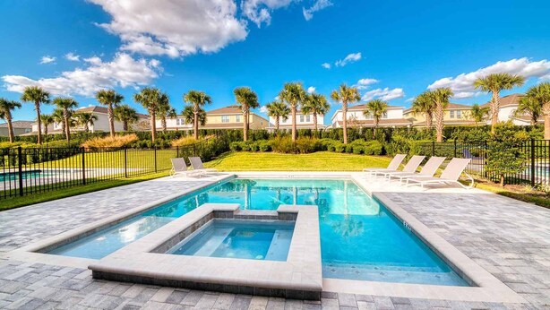 A rectangular swimming pool with a built-in hot tub, surrounded by a paved deck. - Colorful Villa with Theater at Encore (Kissimmee)