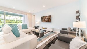 A modern living room with a sofa set, a coffee table, and a painting on the wall. - Colorful Villa with Theater at Encore (Kissimmee)