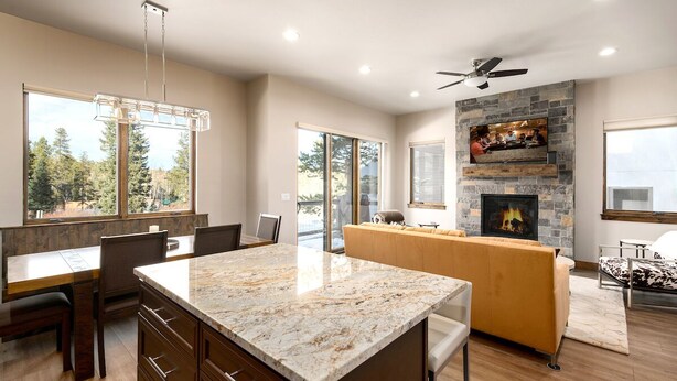 Una cocina moderna con una isla grande, una chimenea de piedra y un comedor con vistas al exterior.
