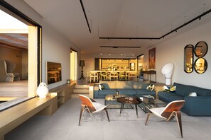 Una sala moderna con un sofá, dos sillones, una mesa de centro y un comedor con sillas y una mesa.