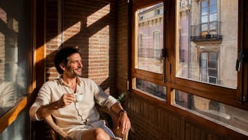 Una persona seduta vicino a una finestra con vista su un edificio, pareti di legno e una struttura in mattoni all'esterno.