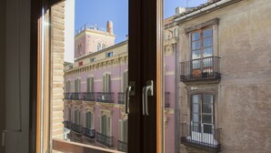 Une vue à travers la fenêtre d’un immeuble doté de balcons, d’une porte et surplombant un ciel dégagé.