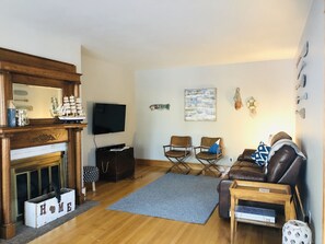 Uma sala de estar com lareira, televisão, sofá e mesa de centro.