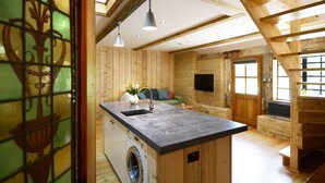 Een kleine keuken met een ingebouwde wasmachine, houten wanden en een accentmuur van steen.