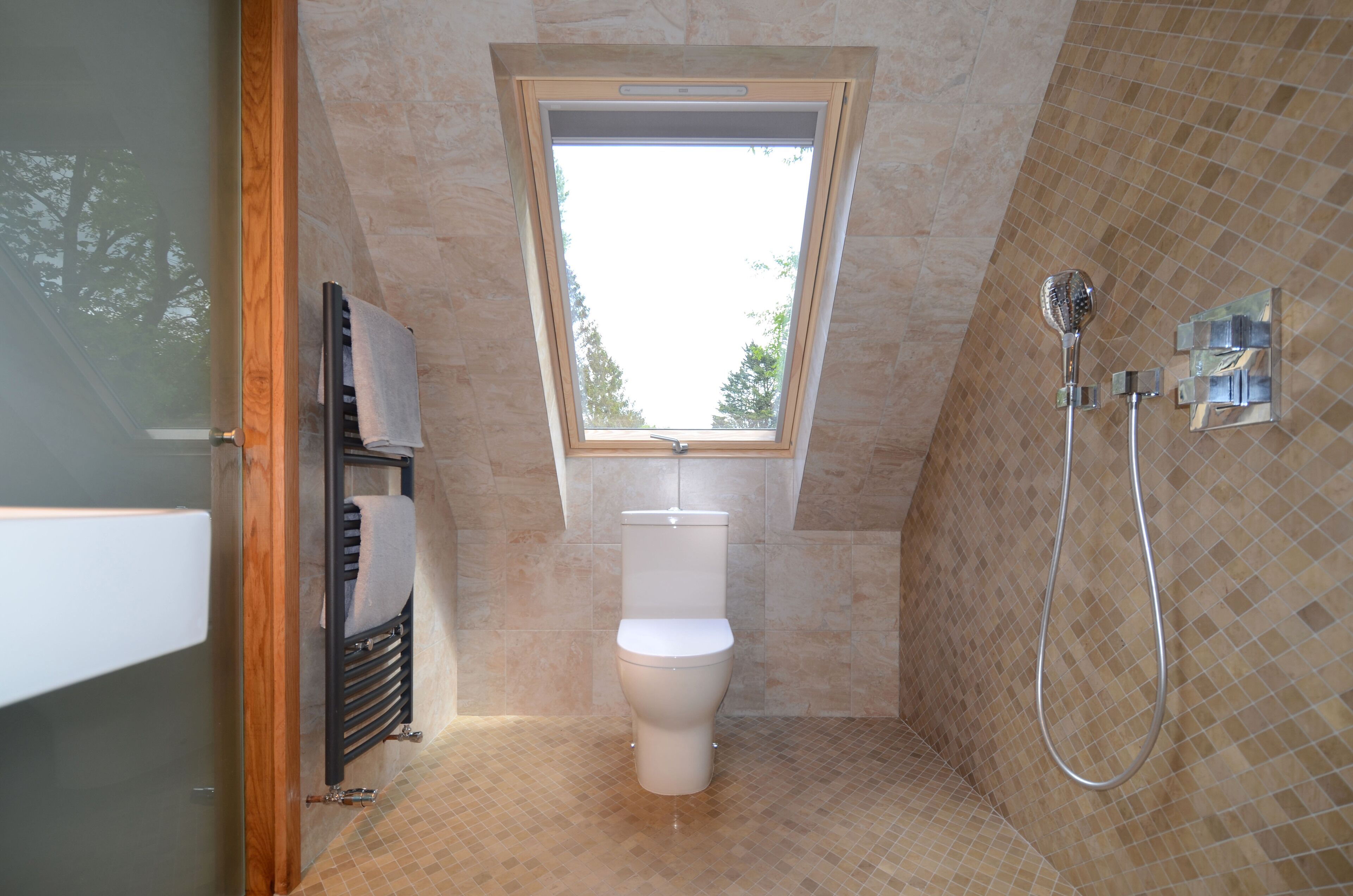 Un bagno con finestra sul tetto, un water, una doccia e un porta asciugamani.