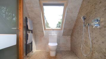 Un bagno con finestra sul tetto, un water, una doccia e un porta asciugamani.