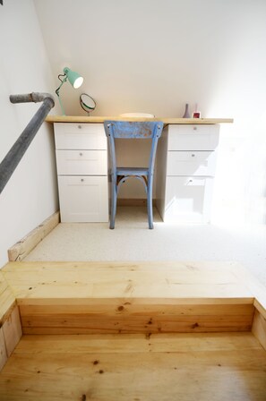 Une petite pièce, de taille modeste, comprenant un bureau en bois, une chaise et une petite lampe.