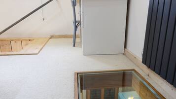 A compact kitchen with a built-in refrigerator, a wooden countertop, and a small window.