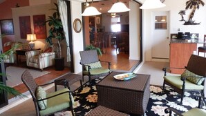A spacious living area with wicker furniture, a large mirror, and a dining area with a wooden table and chairs. - Privacy in Paradise, full refund*, heated pool, sleeps 6 (Rotonda West)
