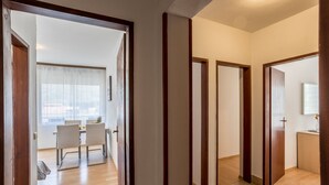 Un corridoio con porte in legno, una sala da pranzo con tavolo e sedie, e vista sull'esterno.