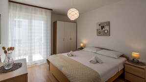Un dormitorio moderno con una cama grande, lámparas de noche, un armario y un adorno en la pared.