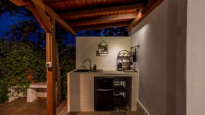 Un área de cocina exterior con pileta integrada, máquina de café y refrigerador.