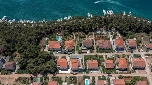 Vista aérea de una zona residencial costera con casas, una piscina y barcos al fondo.