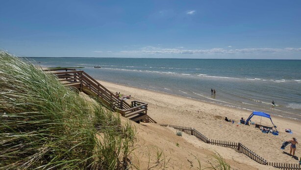 Een strand met een houten looppad, zand en de oceaan.