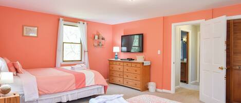 A bedroom with two beds, a dresser, a television, and a door leading to another room.