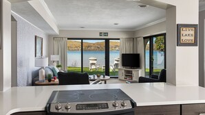 Een moderne keuken met een eiland, een eethoek met uitzicht op een meer, en een zithoek met televisie.