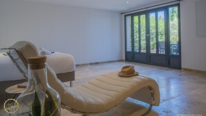 Un transat, une bouteille d’huile d’olive, un chapeau et une petite table avec un livre.