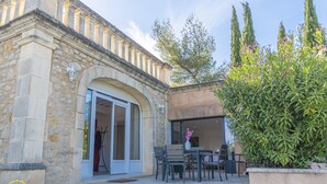 Un bâtiment en pierre doté d’une porte en arc de cercle et d’un patio aménagé avec des sièges extérieurs.