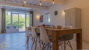 Un coin repas avec une table en bois, quatre chaises et des lampes suspendues.