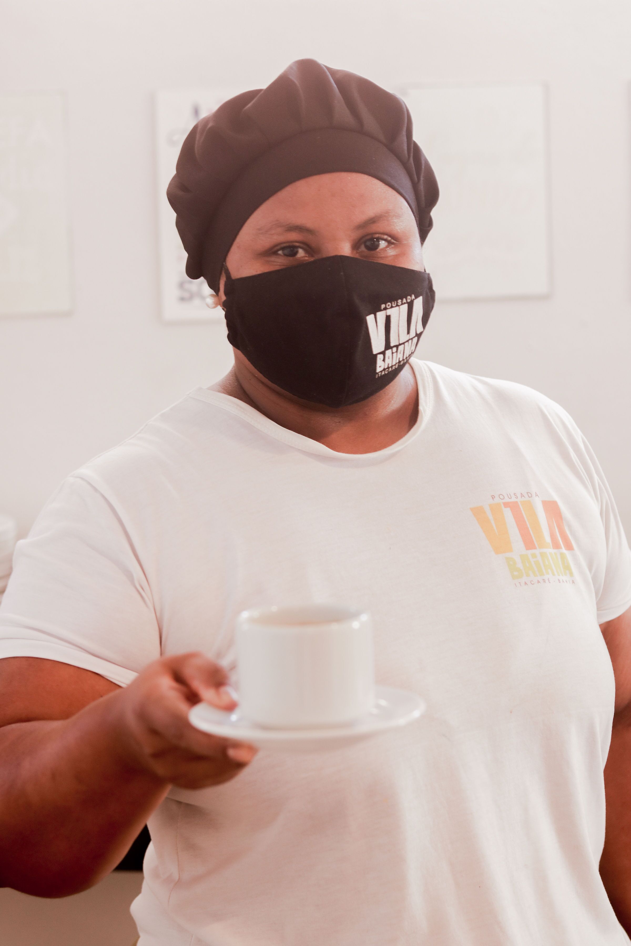 A person holding a white cup and saucer.