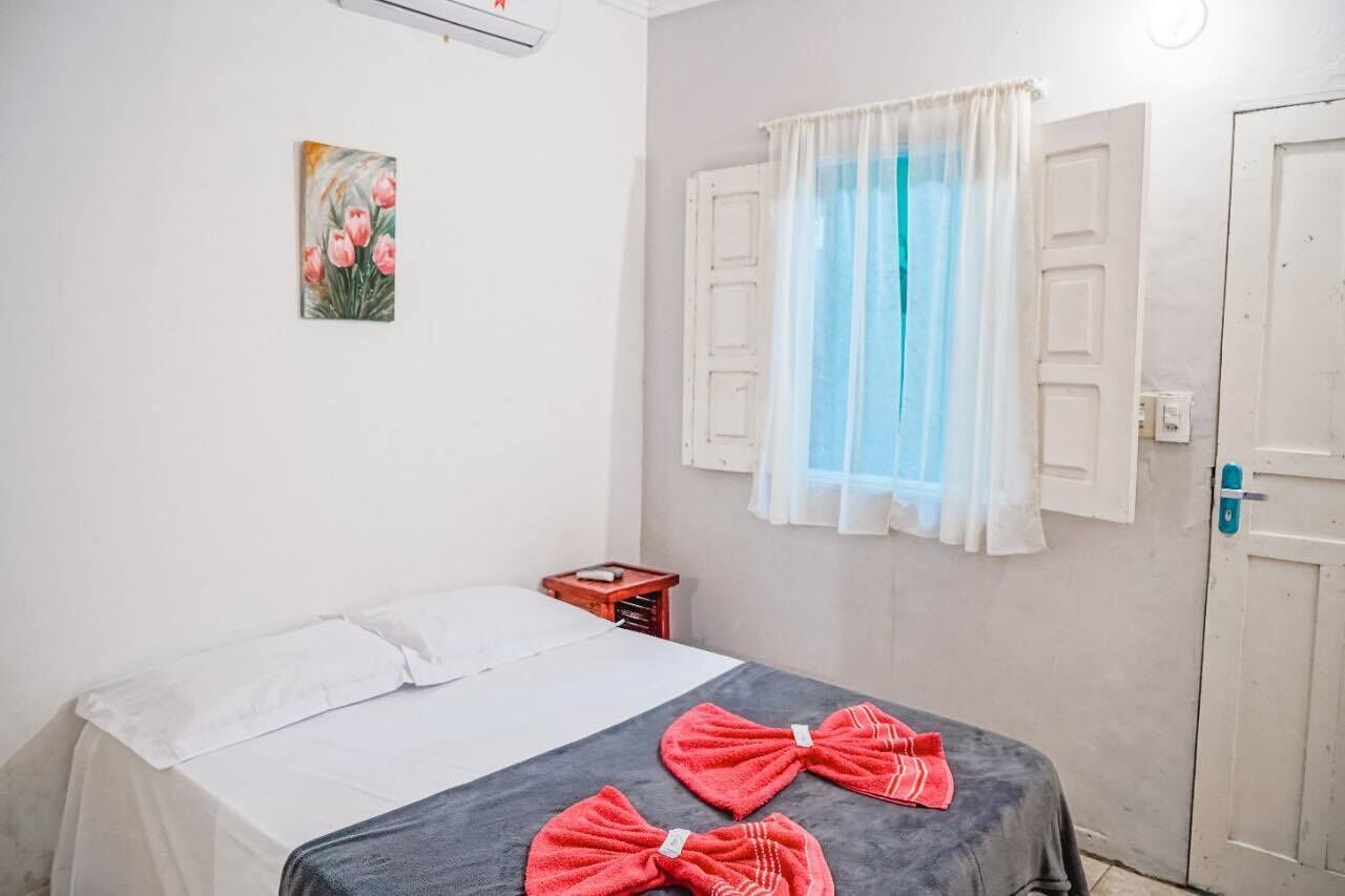 Un dormitorio con cama, un cuadro, una ventana con cortinas y una puerta.