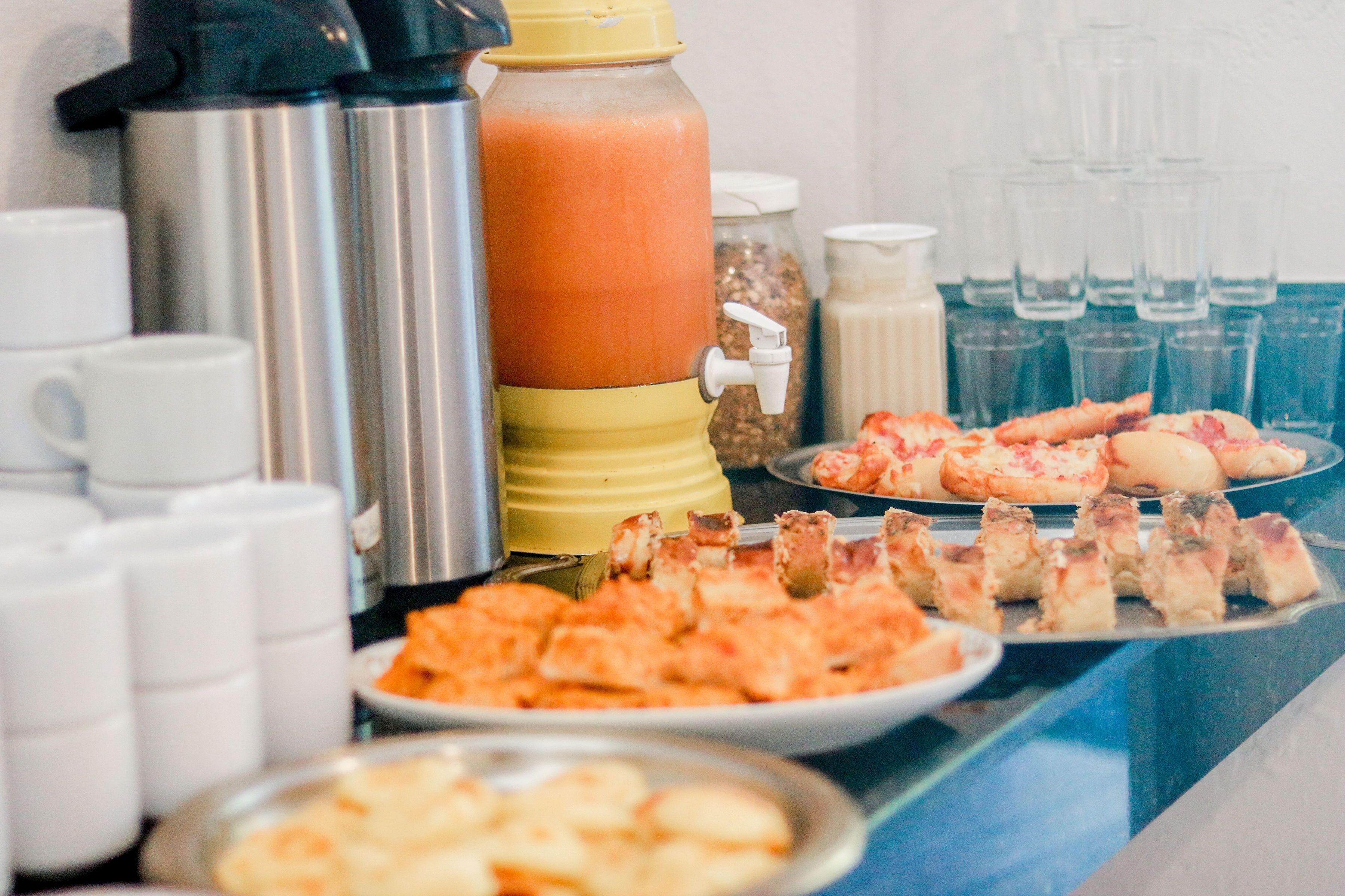 A buffet table with various food items, including pizza and bread, and beverage dispensers.