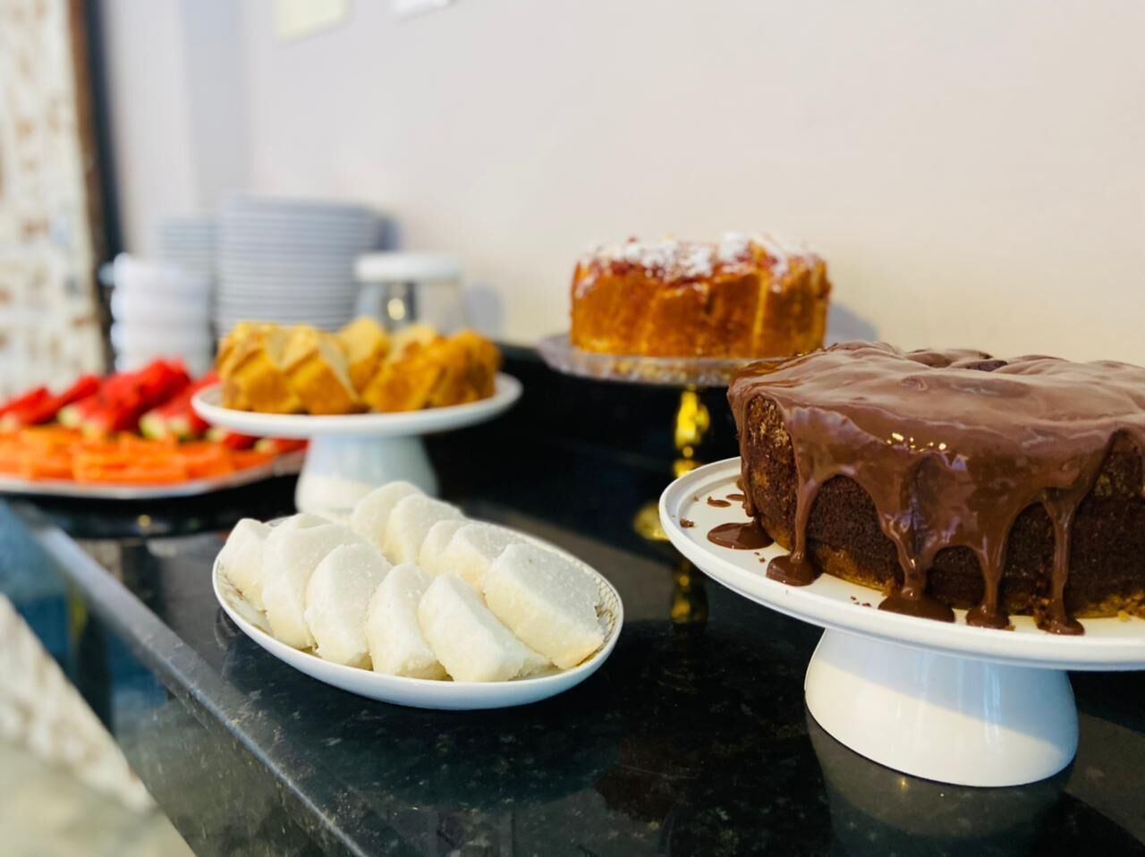 Ett buffébord med olika sorters desserter, inklusive en chokladtårta, ljusa bakverk och en fruktfat.