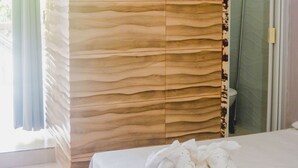 Habitación de hotel con cama, ventilador de techo, unidad de aire acondicionado, ducha y panel de pared de madera.