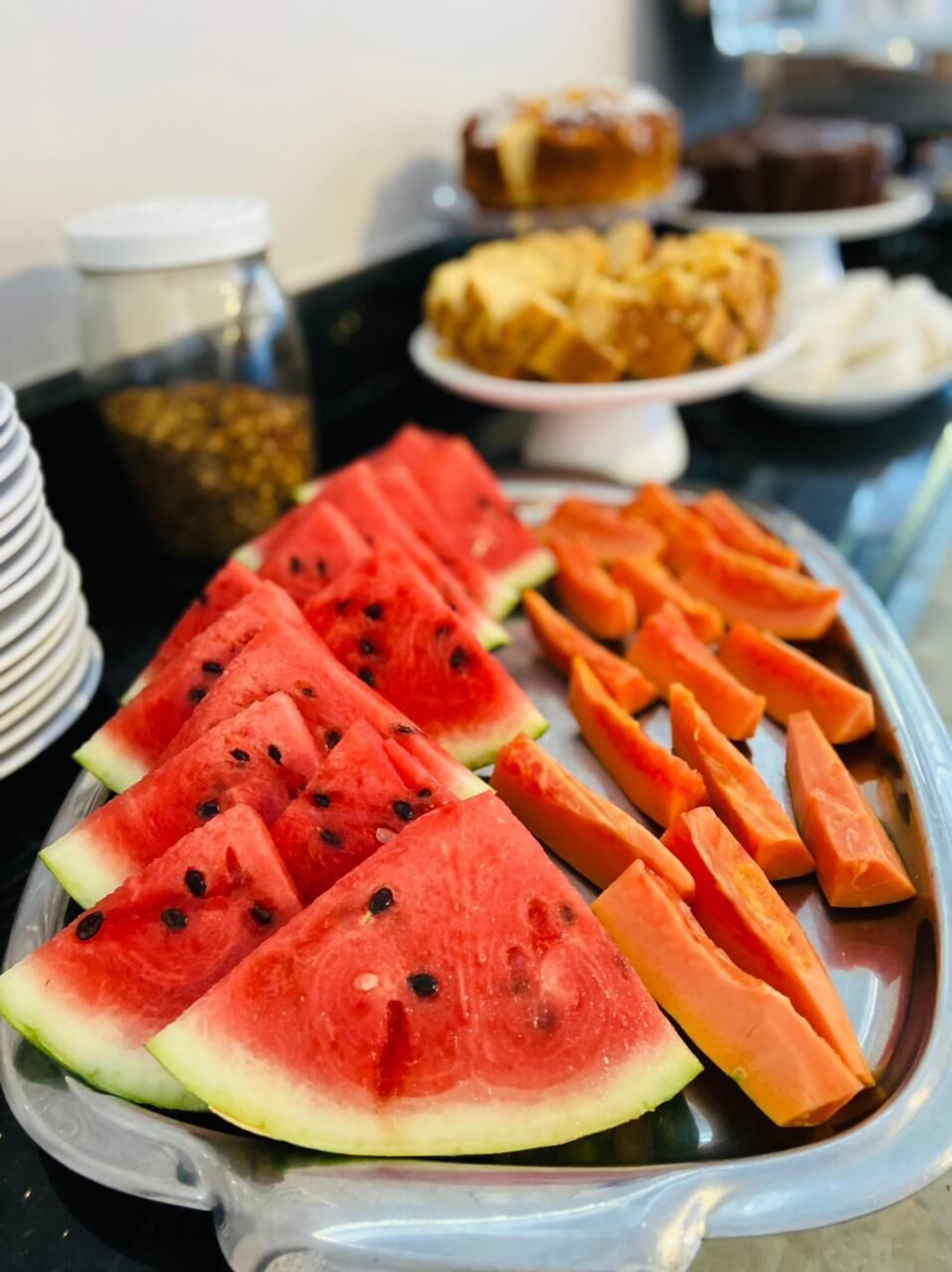 A buffet table with watermelon slices and carrot sticks.