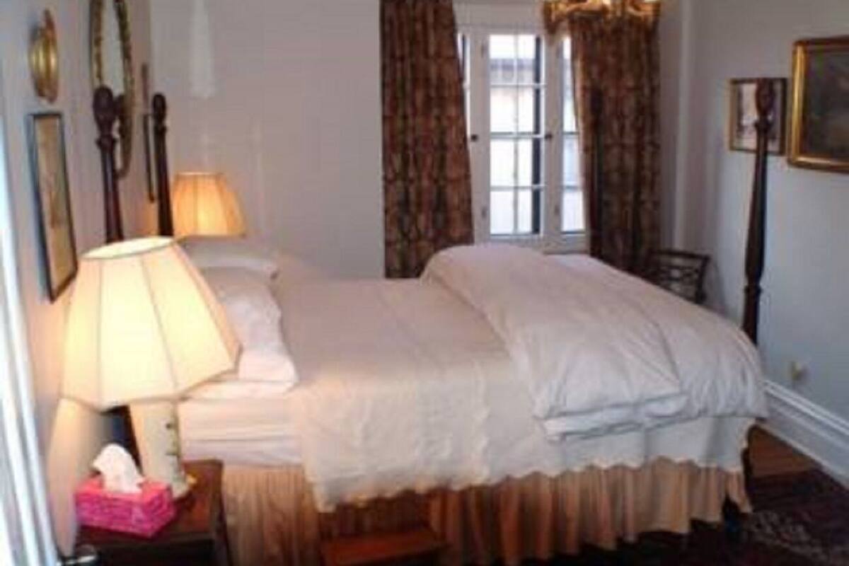 A hotel room with a large bed, a bedside table with a lamp, a chair, and a window with curtains.