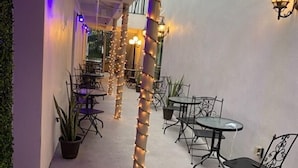 An outdoor seating area with tables and chairs, string lights, and a potted plant. - Dunns Josephine Hotel (Miami)
