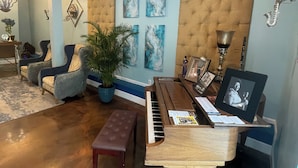 A living room with a grand piano, comfortable seating, a large plant, and a decorative wall. - Dunns Josephine Hotel (Miami)