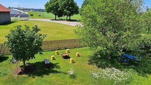 A grassy area with trees, a wooden fence, and a building with a red roof.