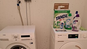 A laundry area with two washing machines, a TANDIL detergent box, and a TANDIL bottle.