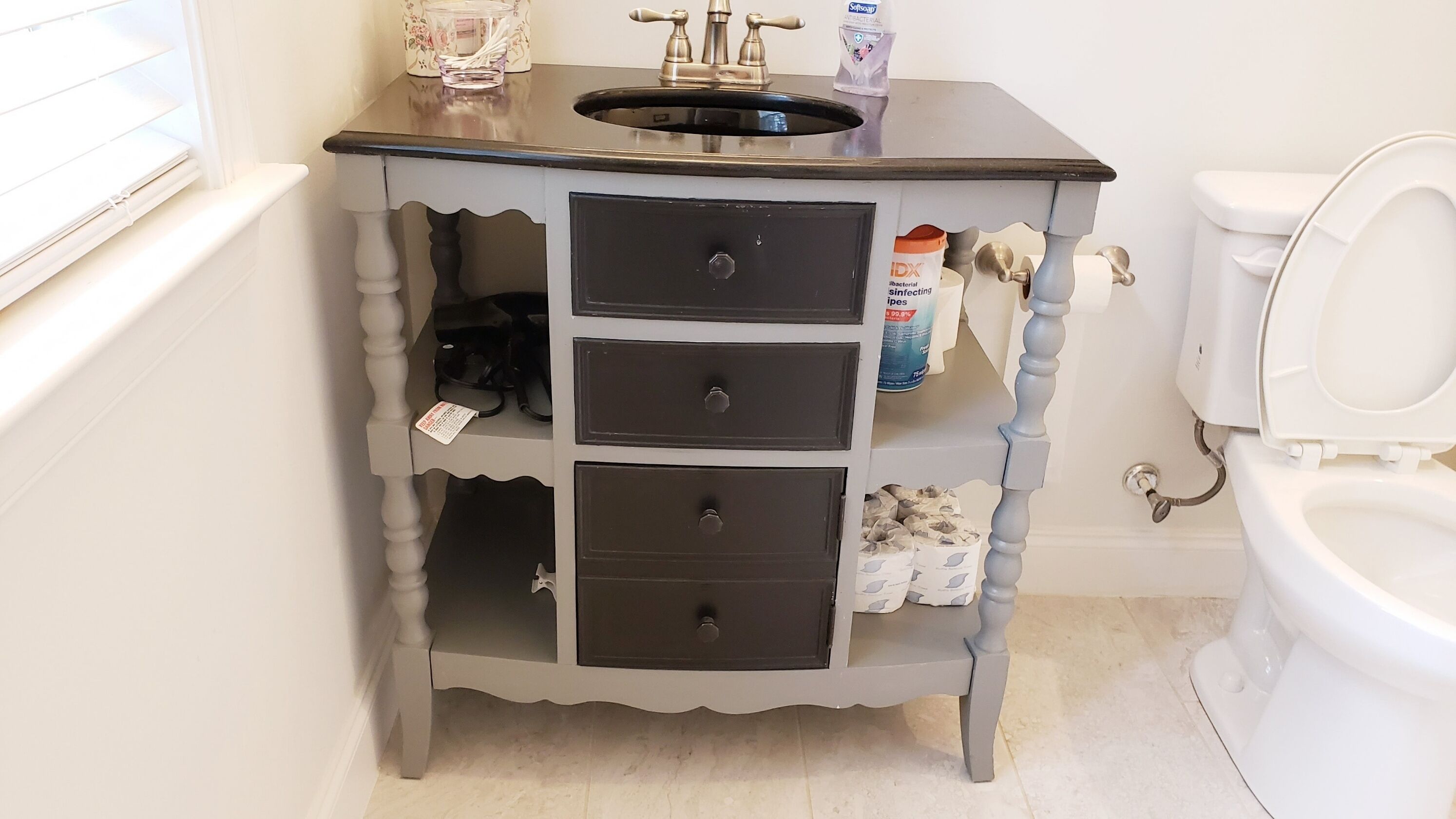 A bathroom with a white toilet, a sink with a faucet, and a cabinet with drawers.