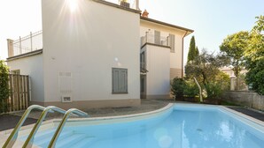 Une piscine située à côté d’un bâtiment doté d’un balcon.