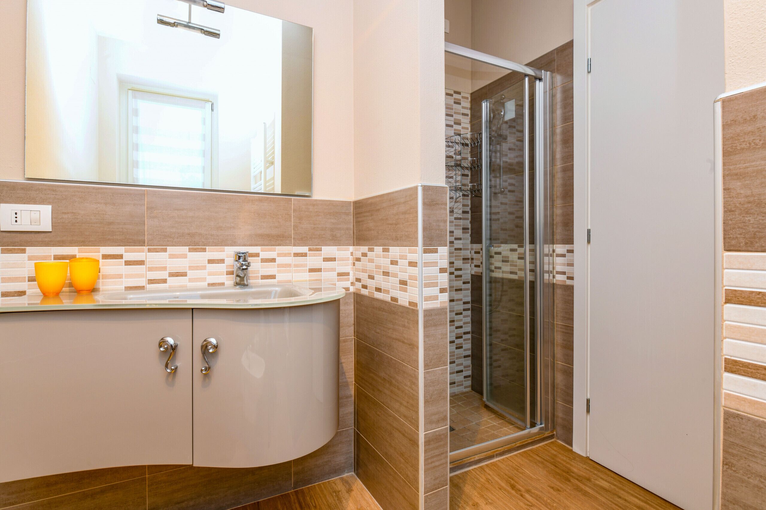 Une salle de bain moderne avec un meuble-lavabo aux lignes courbes, une douche en verre et un grand miroir.